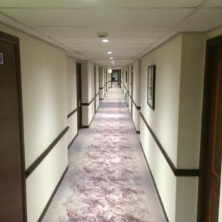 A long hotel corridor with a patterned carpet running down the middle and doors lining both sides