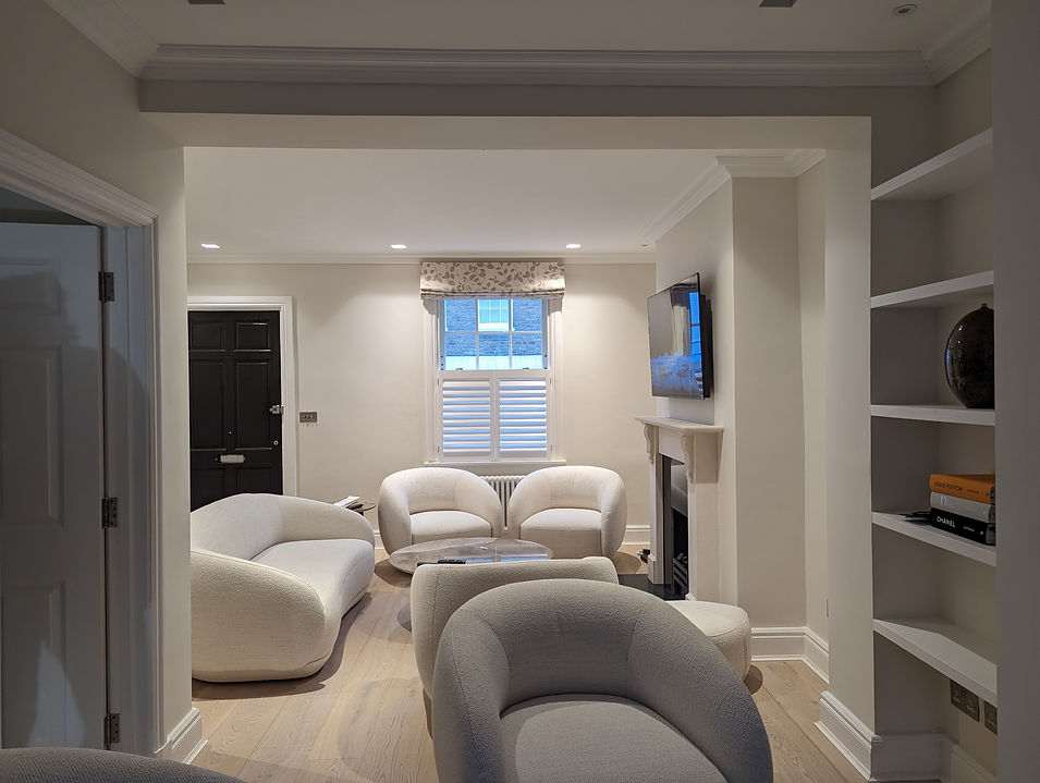Stylish living room with creamy white curved seating, a fireplace, and a window with half-height shutters