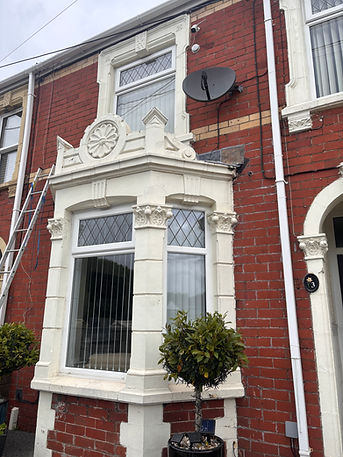 Traditional brick terraced house featuring white window frames decorative masonry and roof dormer