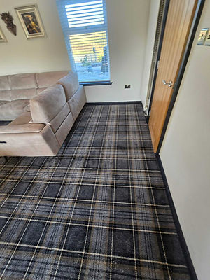 High quality dark grey and white tartan patterned carpet installed in a modern living room next to a neutral sofa