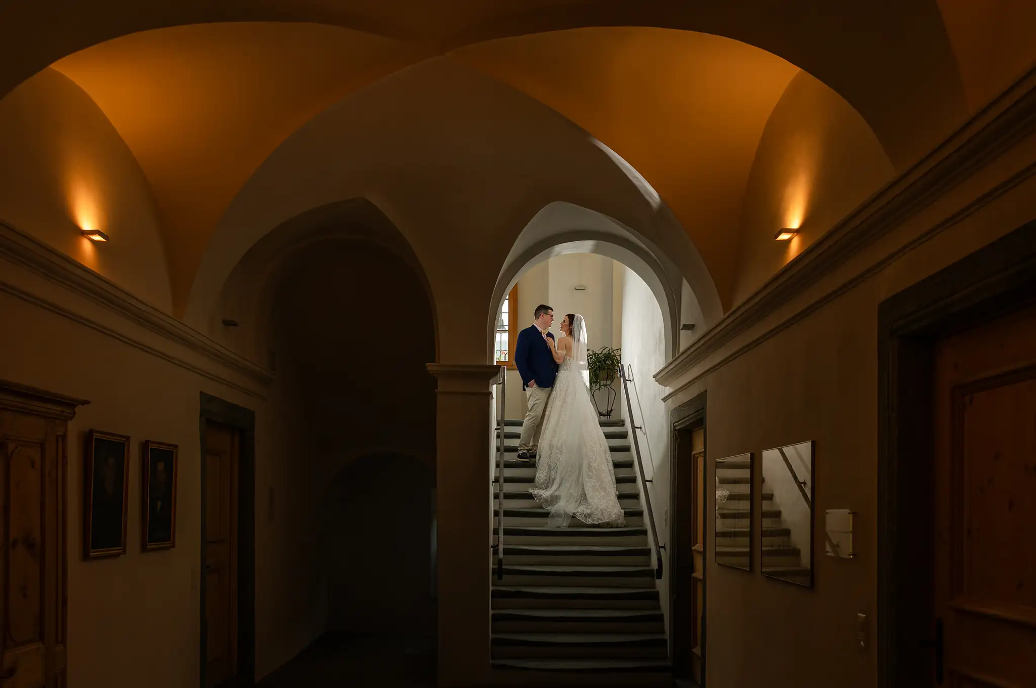 Brautpaar steht im dramatischer Location mit hohen Räumen und schönen warmen Licht