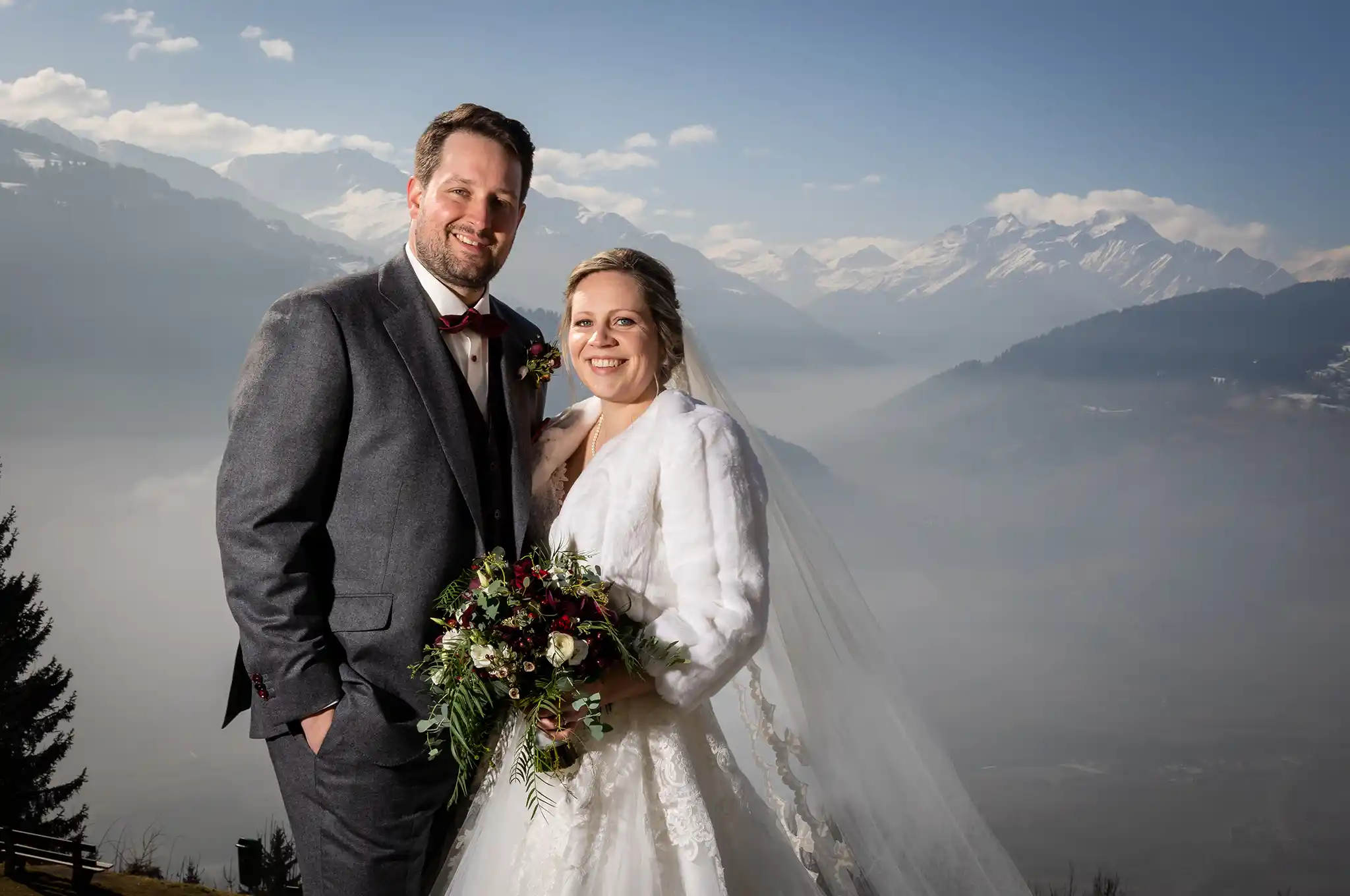 Brautpaar in Winterlichen Hochzeitsoutfit vor Hochnebel und Bergen