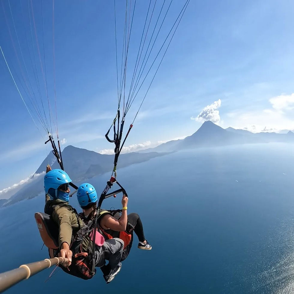 Soaring above the stunning landscape, a paragliding duo enjoys breathtaking views of mountains and a serene lake in paradise.