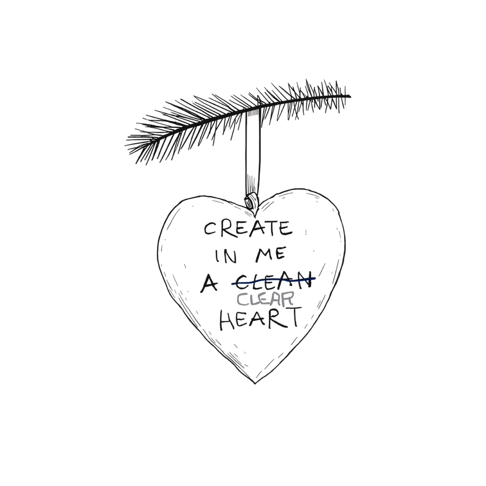 A handmade white clay Christmas ornament shaped like a heart with the words “Create in me a clean heart” written in a child’s handwriting.