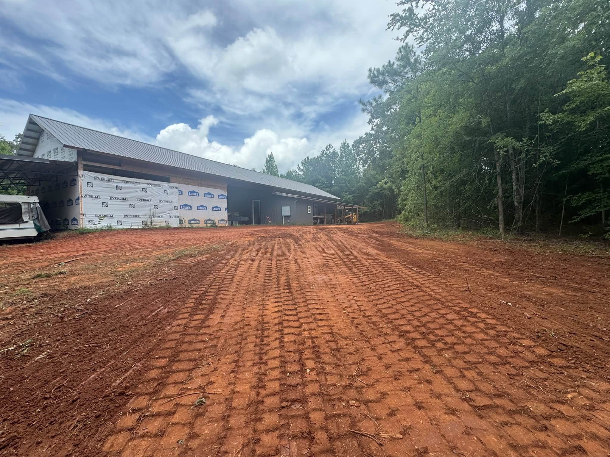 Freshly graded red clay site beside a new shop building in Monticello, GA