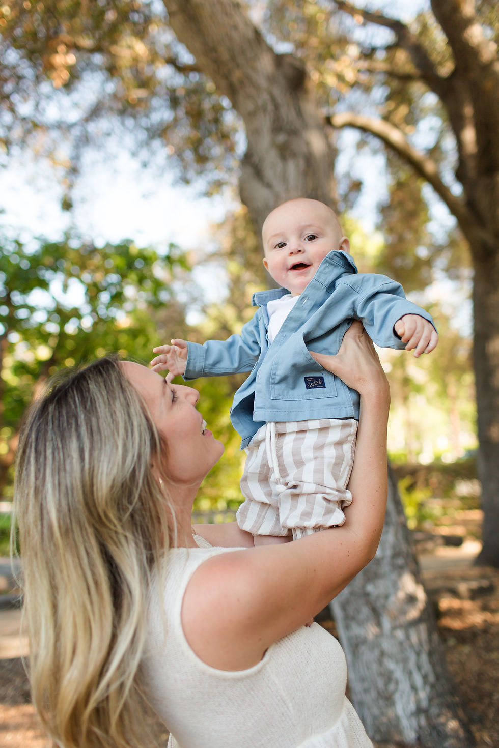 Smiling woman lifts baby in blue jacket under trees, both looking happy outdoors.
Spring Family Photoshoot at Elizabeth Gamble Garden, Palo Alto by Bay Area Photographers HKCreate