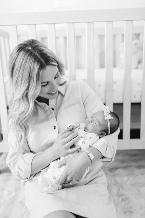 hkcreate bay area photography joyful candid light and airy lifestyle newborn photoshoot san jose photographers neutral colors pink cream baby girl black and white image of mama holding baby girl sitting on the floor against the crib in the nursery