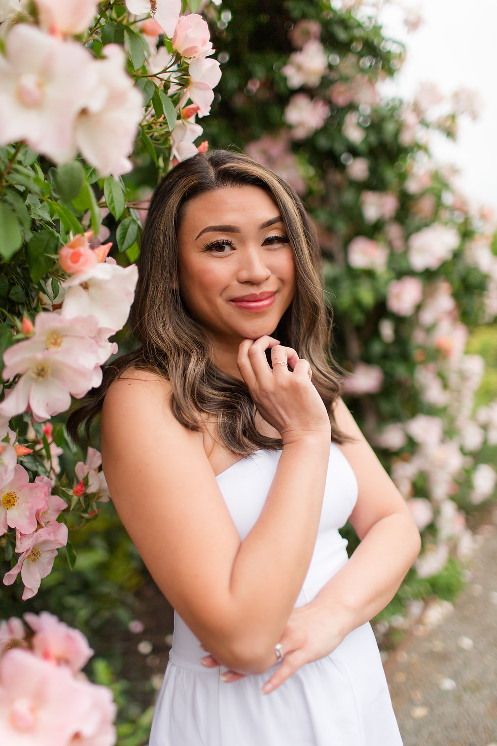 Smiling woman in a white dress poses among pink blossoms in a lush garden.
Samuel Merritt University Spring Grad Photoshoot by HKCreate Bay Area Photographers 
Filoli Historic House and Garden, Woodside 