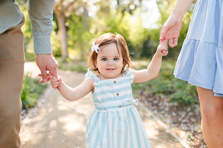 parents holding little girl toddler hands in blue stripe dress at a garden bay area photography hk create