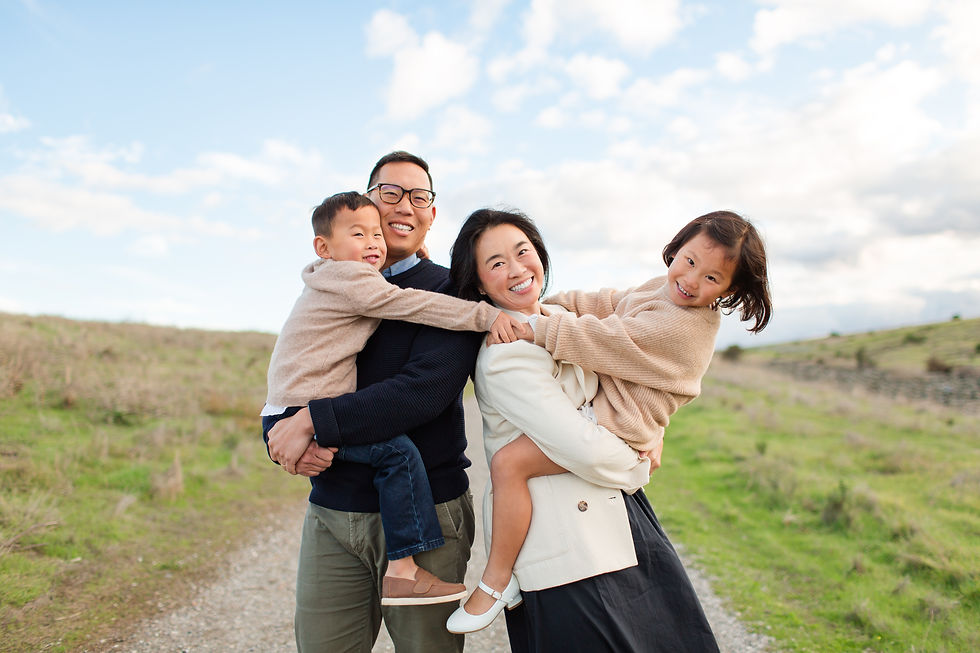 Smiling family in open field. Parents hold children, one on each arm, wearing cozy sweaters. Bright day, blue sky with clouds.
Byxbee Bayfront Park in Palo Alto Winter Family Photoshoot by HKCreate Bay Area Photographers