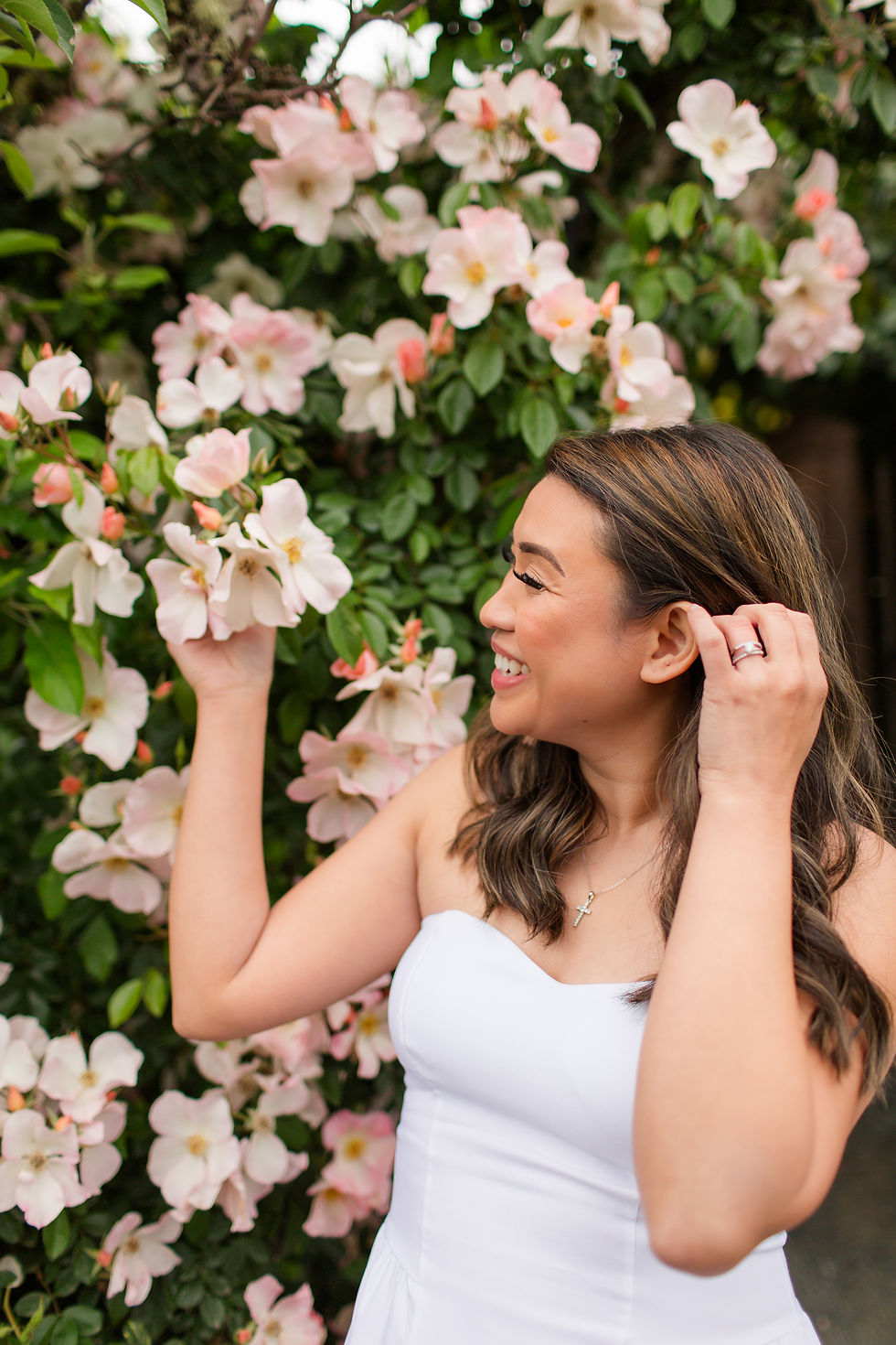 Smiling woman in a white dress touches pink blossoms on a leafy wall, wearing a cross necklace.
Samuel Merritt University Spring Grad Photoshoot by HKCreate Bay Area Photographers 
Filoli Historic House and Garden, Woodside 