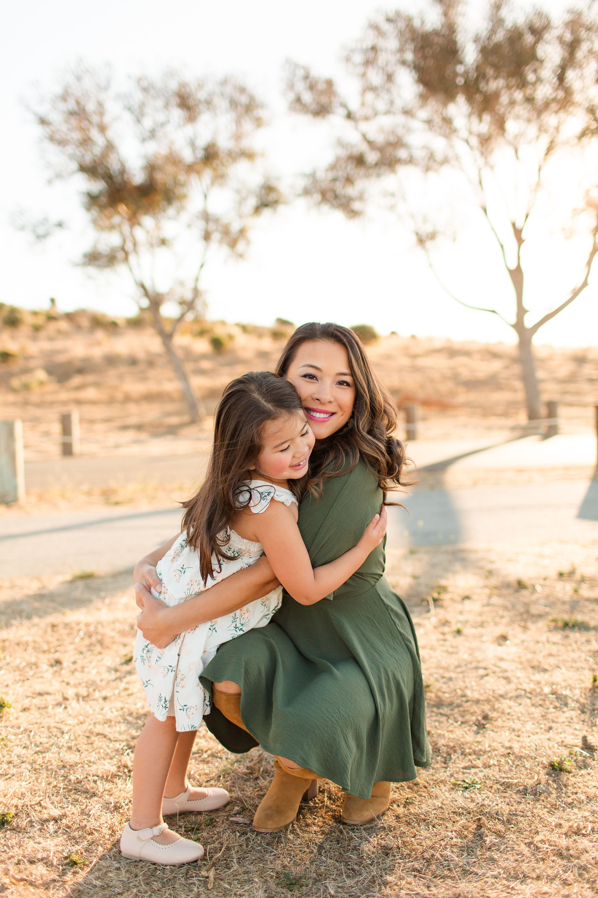 hkcreate bay area photography joyful candid light and airy san jose photographers northern california photoshoot. Family of Four fall photoshoot with green, sage, blue and tan color scheme. Cute and fun photoshoot at Byxbee Bayfront Park in Palo Alto. Mom giving a hug to daughter.