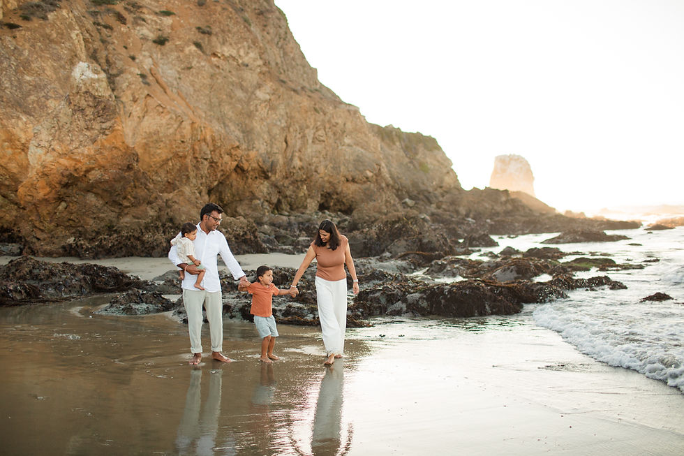 Family of four walks barefoot on a rocky beach at sunset. Warm tones, happy mood. Parents holding kids' hands near water's edge.
Rockaway Beach Pacifica Fun Playful and Cute Family Photoshoot by HKCreate Bay Area Photographers.