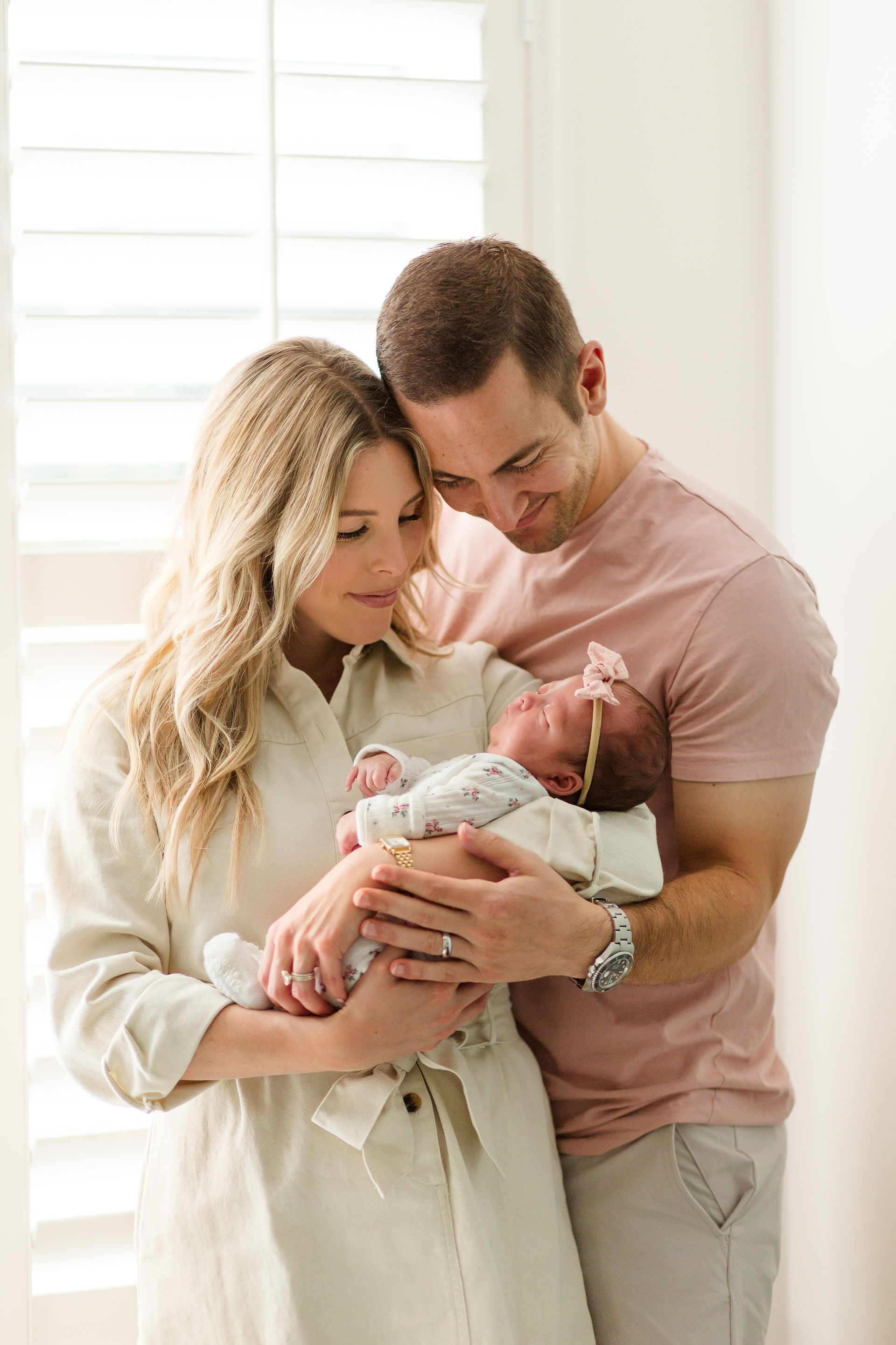 hkcreate bay area photography joyful candid light and airy lifestyle newborn photoshoot san jose photographers neutral colors pink cream baby girl parents holding baby smiling heads together