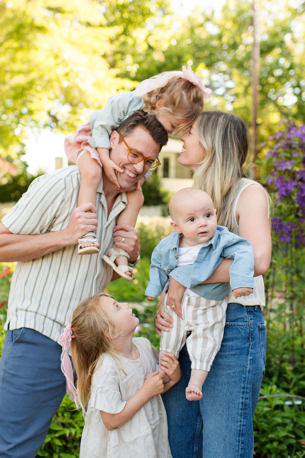 Smiling family of five cuddles in a sunny garden, parents holding a baby and girl, with another child on dad’s shoulders.
Spring Family Photoshoot at Elizabeth Gamble Garden, Palo Alto by Bay Area Photographers HKCreate