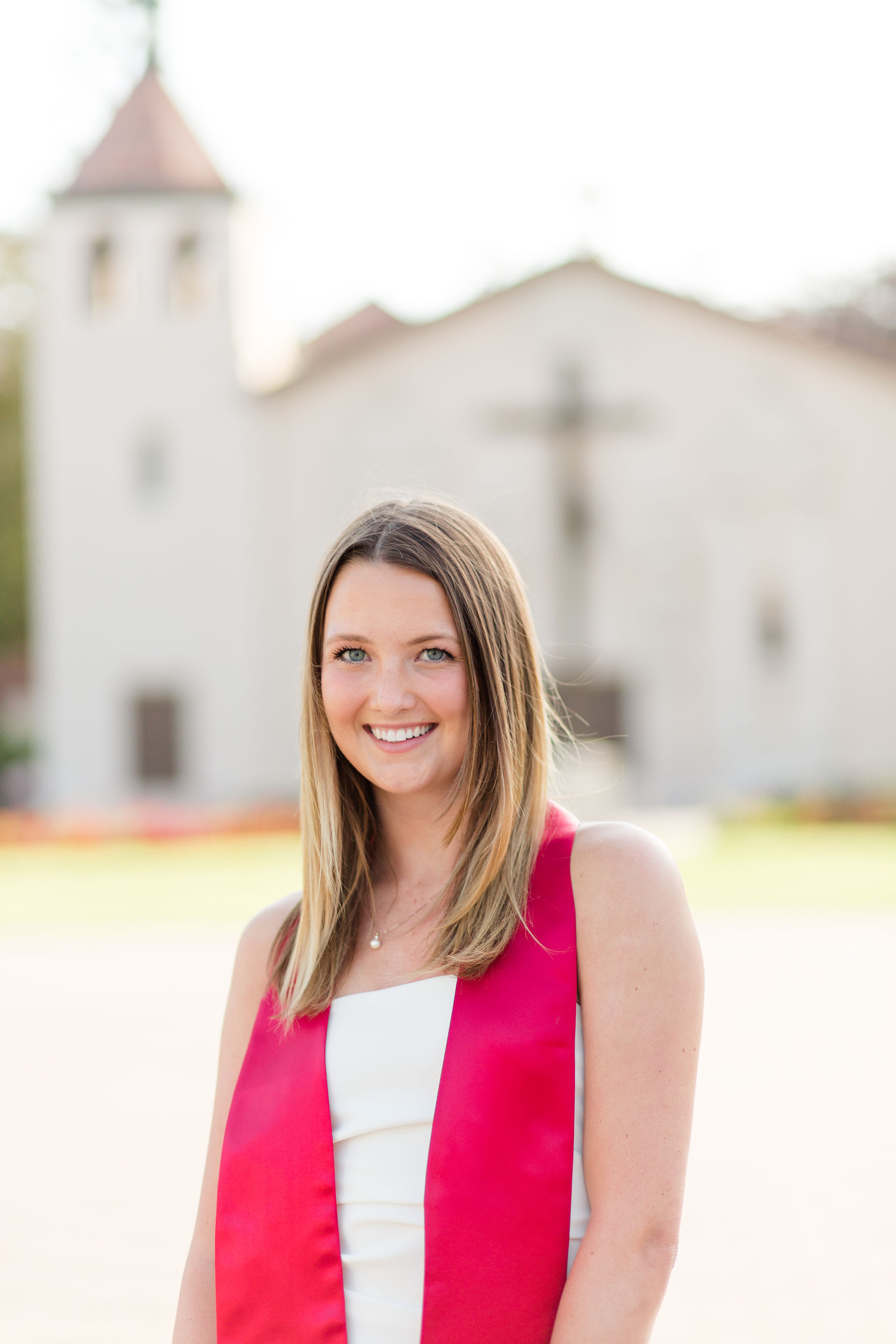santa clara university group graduation session portraits girl wearing red stole and white dress in front of mission