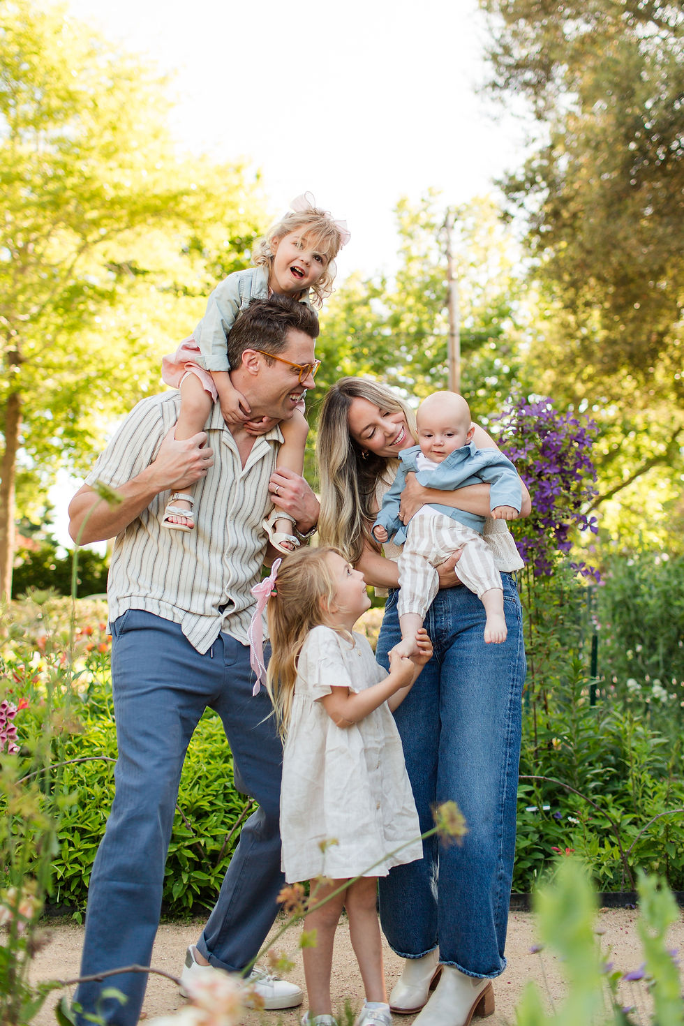 Smiling family of four with two children in a sunny garden, parents holding kids, bright flowers and trees in the background
Spring Family Photoshoot at Elizabeth Gamble Garden, Palo Alto by Bay Area Photographers HKCreate