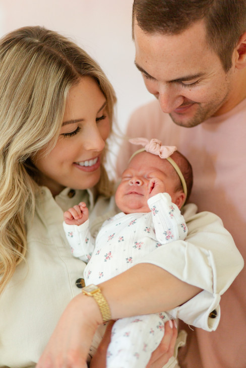hkcreate bay area photography joyful candid light and airy lifestyle newborn photoshoot san jose photographers neutral colors pink cream baby girl parents holding baby smiling down