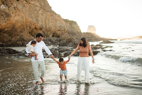 hkcreate bay area photography light and airy natural light ocean beach family of four playing in the water wearing neutrals with orange pops of color at the rockaway beach in pacifica