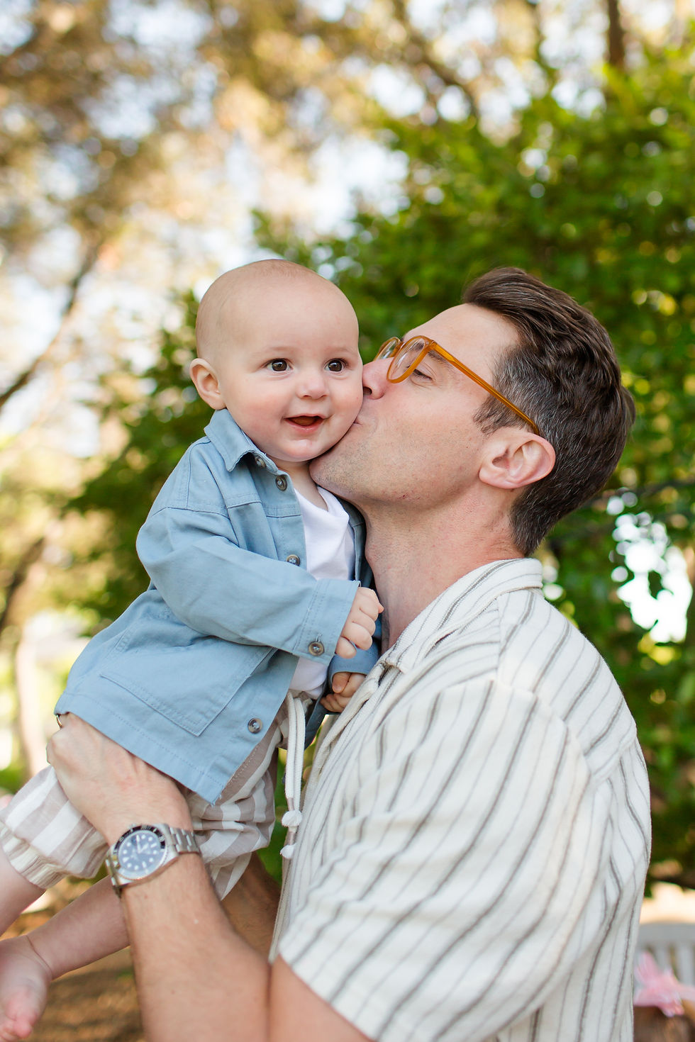Man in glasses kisses smiling baby’s cheek outdoors, baby in blue shirt held against a blurred green tree background.
Spring Family Photoshoot at Elizabeth Gamble Garden, Palo Alto by Bay Area Photographers HKCreate