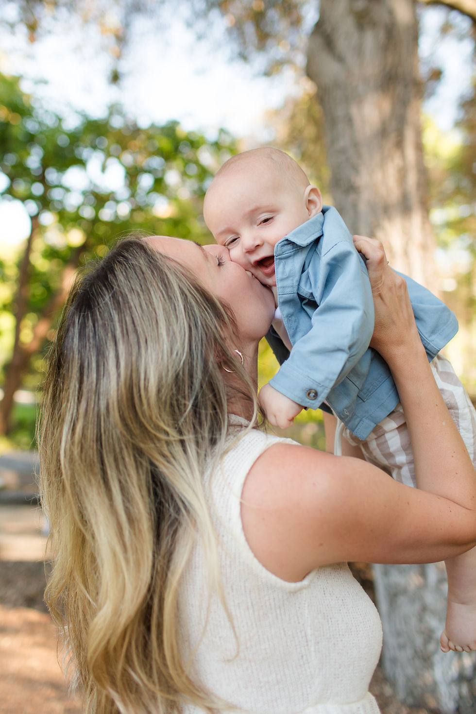 Woman kisses smiling baby in blue shirt outdoors beside a tree, with soft green bokeh background.
Spring Family Photoshoot at Elizabeth Gamble Garden, Palo Alto by Bay Area Photographers HKCreate