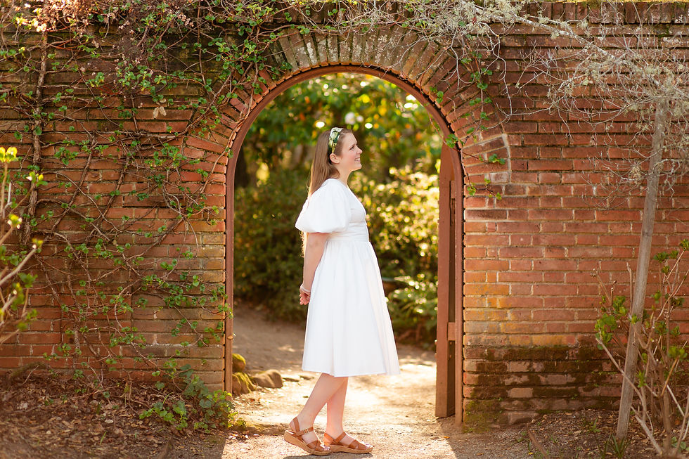 Woman in white dress stands under brick archway, surrounded by greenery. Sunlight filters through, creating a serene, dreamy atmosphere.
Spring High School Senior Graduation Photoshoot by Bay Area Photographers HKCreate at Filoli Historic House and Garden in Woodside, California