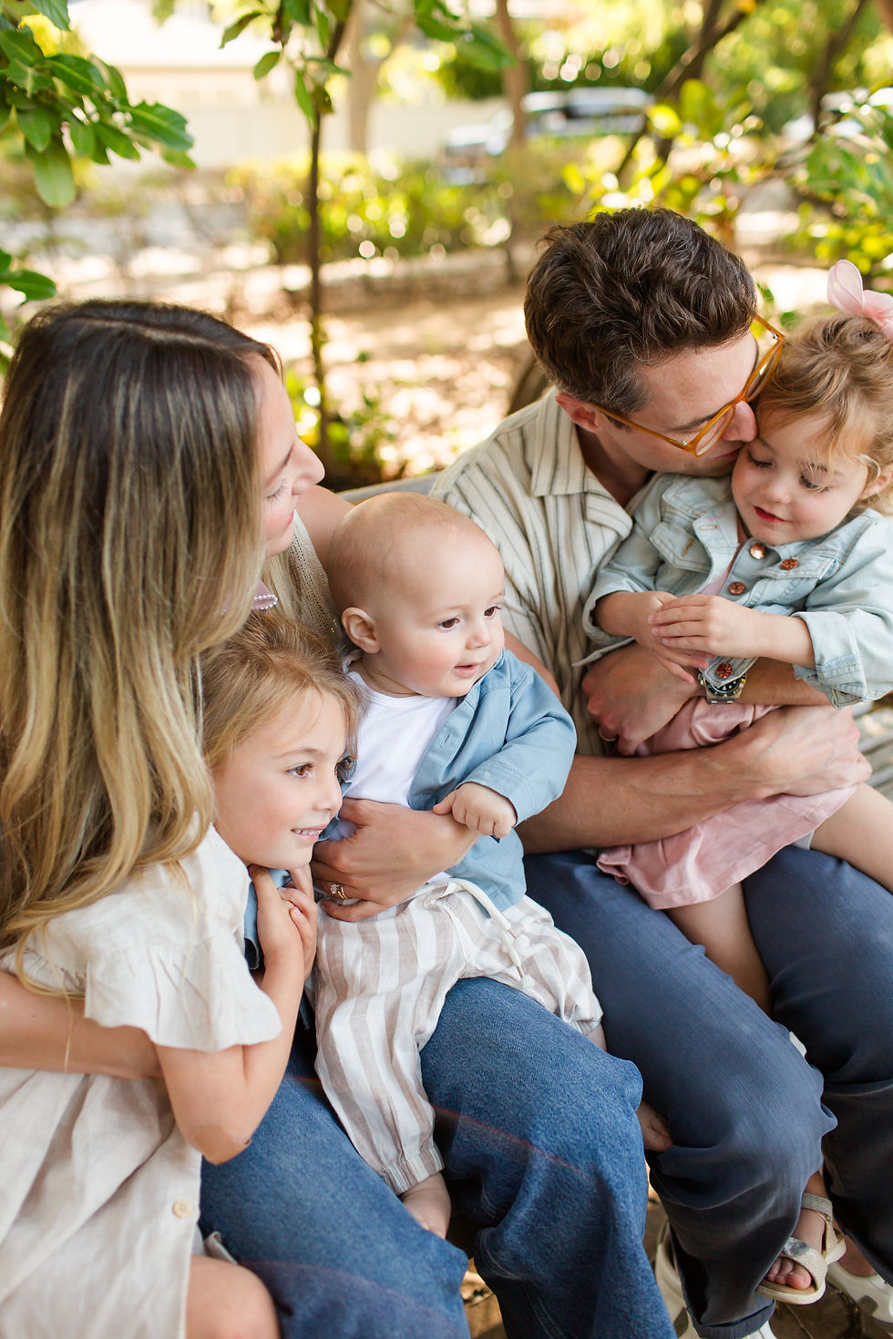 Smiling family of two parents and three young children cuddling on a bench in a sunny garden, warm and affectionate.
Spring Family Photoshoot at Elizabeth Gamble Garden, Palo Alto by Bay Area Photographers HKCreate