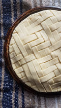 A herringbone latticed pie, unbaked, on a traditional Mexican blanket, or Serape.