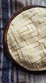 A herringbone latticed pie, unbaked, on a traditional Mexican blanket, or Serape.