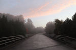 A blue sky with cotton candy clouds setting on a recently rained on bridge. Priceville, ON