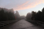 A blue sky with cotton candy clouds setting on a recently rained on bridge. Priceville, ON