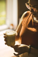 A woman wearing a red shirt holding a jar of sourdough starter and talking about it.