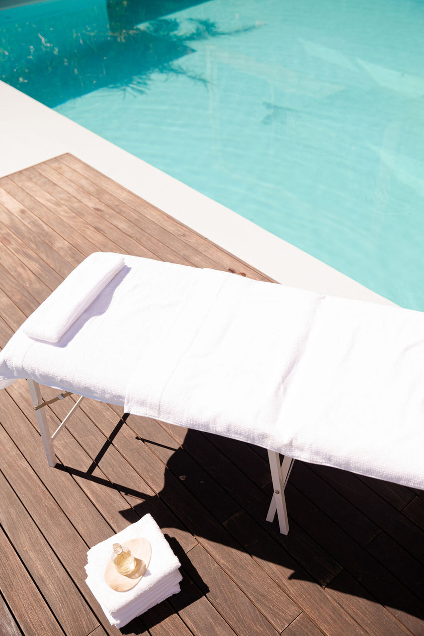 Massage table poolside with towels and a glass of water
