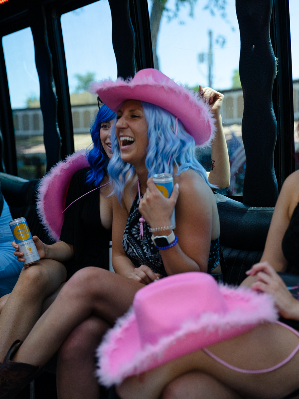 Group of women in cowboy hats laughing on a party bus