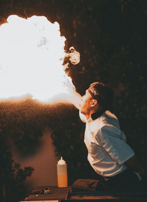 Hibachi chef performing a fiery show with a large flame