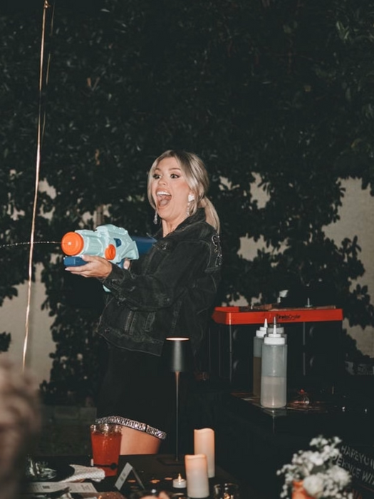 Woman holding a water gun and smiling at a Scottsdale bachelorette party