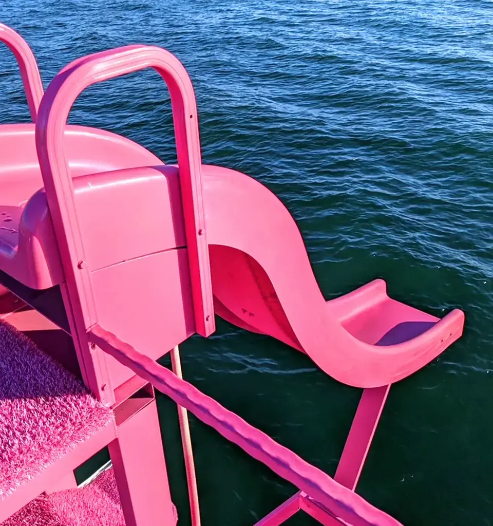 Pink waterslide extending over blue water