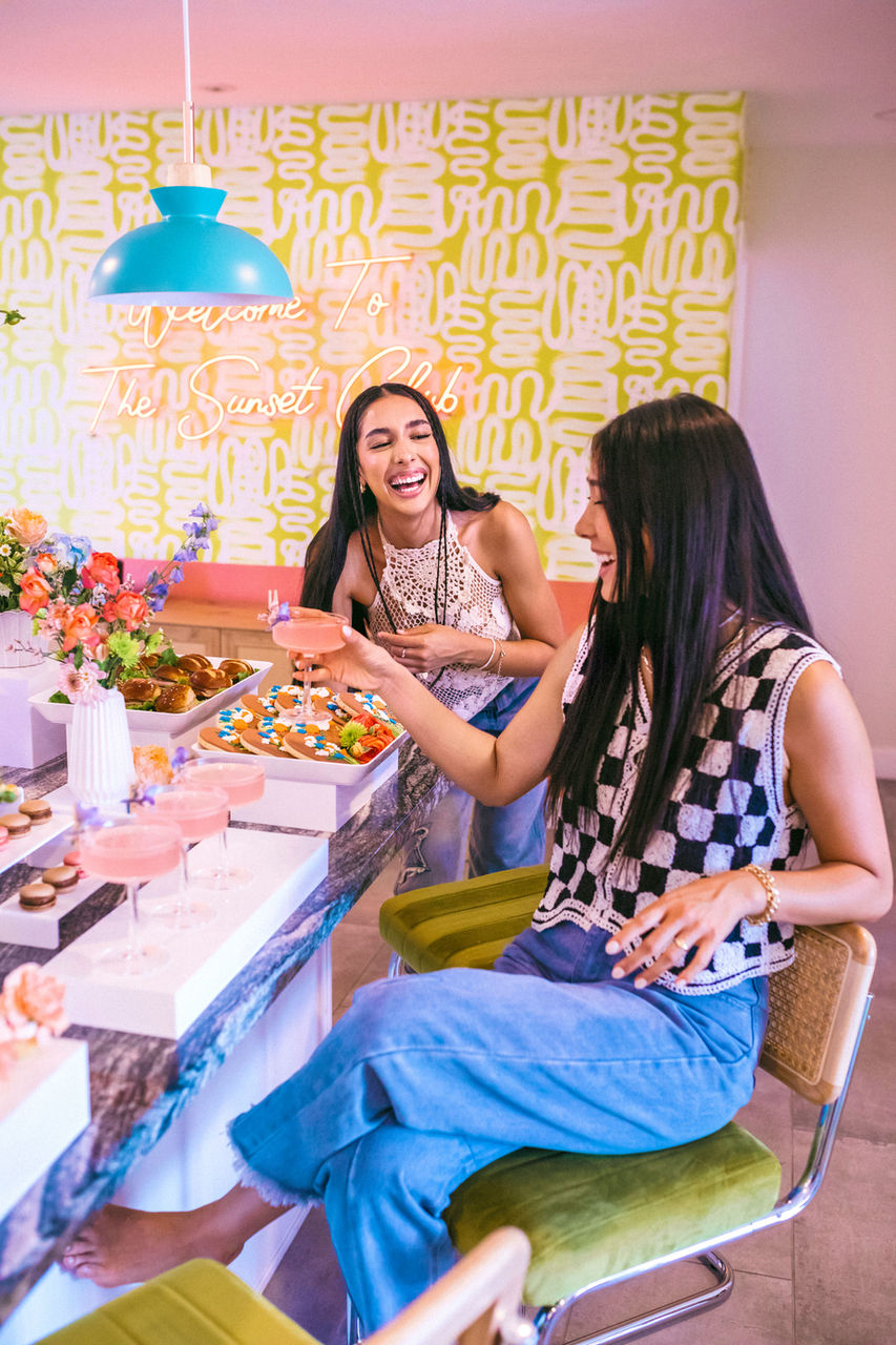 Two women laughing at a table with drinks and snacks, Scottsdale Bachelorette Demo