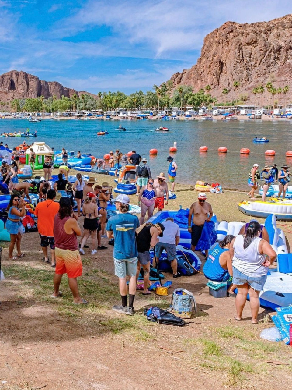 Large group of people gathered on a sandy beach preparing for a tubing trip on the Salt River