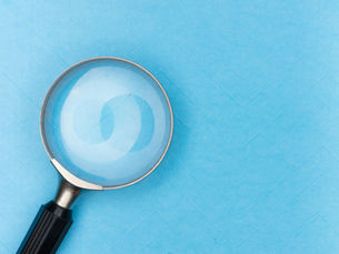 Zoek Marketing represents search engine optimization with an image of a magnifying glass on a blue file folder background. The glass reflects light, showing faint patterns. No text is visible.