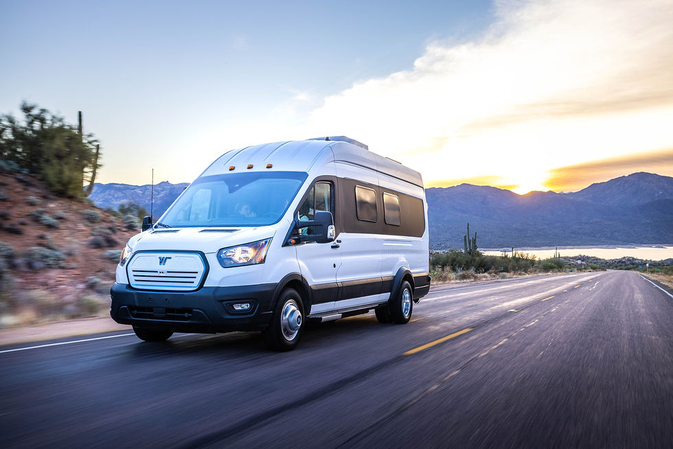 White camper van driving on a scenic desert road at sunset, with mountains and cacti in the background. Road and sky emphasize adventure.