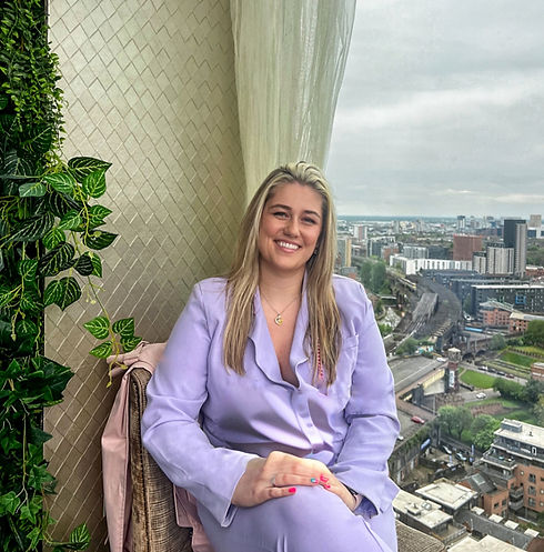 Image of Dr Cheryl Venart, woman with blonde hair wearing purple suit smiling with leg crossed over the other