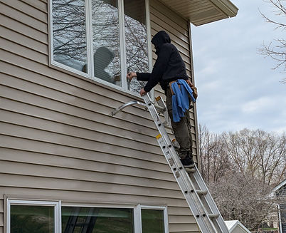 Owner Jackson Weinberg cleaning exterior windows on a ladder – expert window cleaning in the Twin Cities by Red Eye Exterior