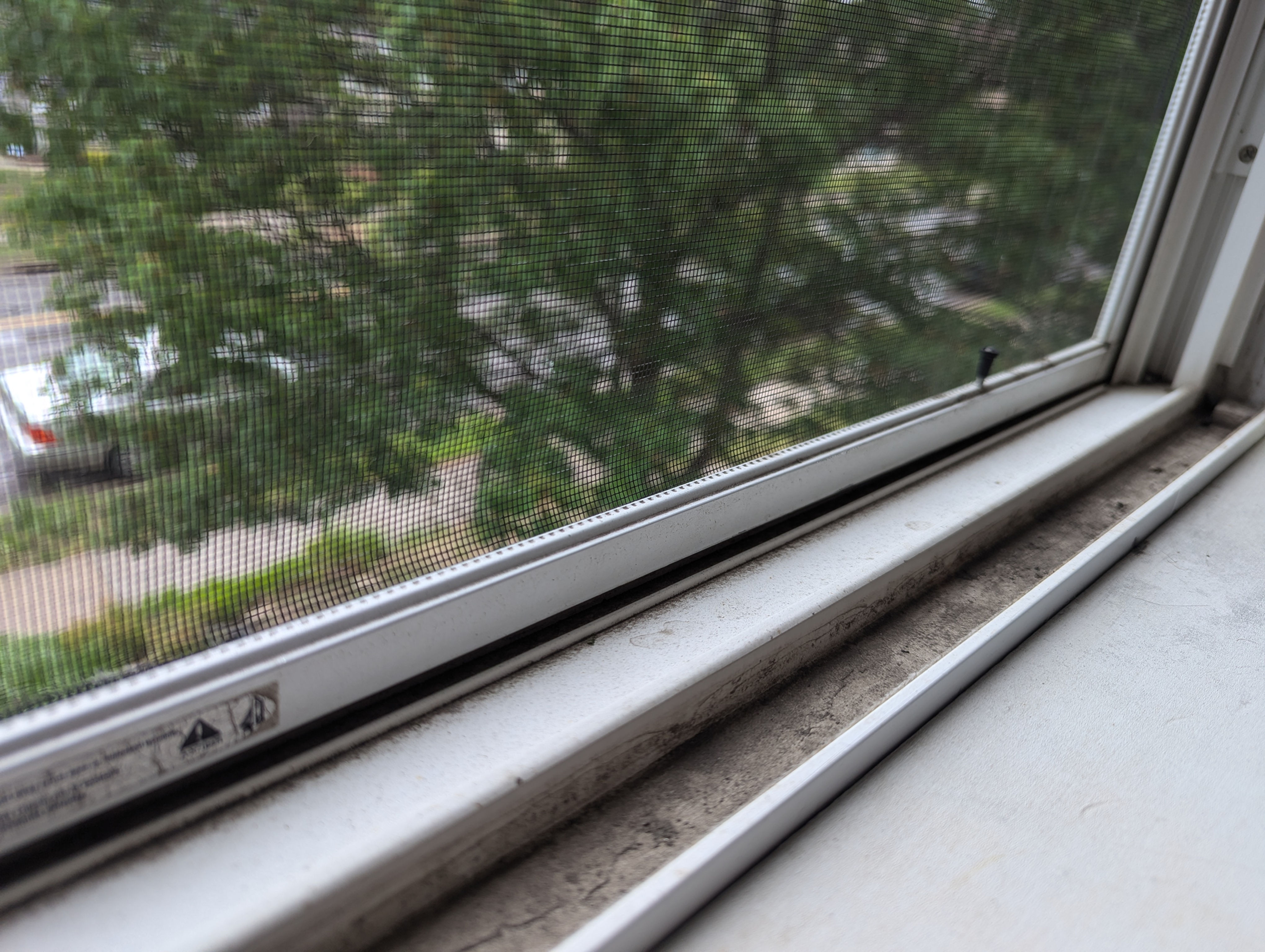 Close-up of a dirty window track filled with debris before professional cleaning in a Twin Cities home.