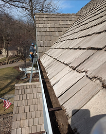 Jackson Weinberg, owner-operator of Red Eye Exterior Cleaning, clearing gutters by hand in Rosemount