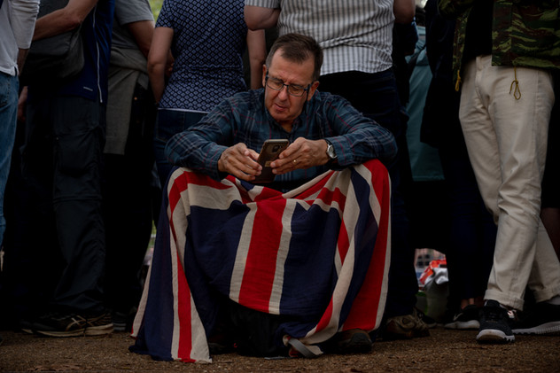 14th September 2022 | A man resting on The Mall while waiting for the procession to bring Queen Elizabeth's coffins from Buckingham Palace to Westminster Hall.
