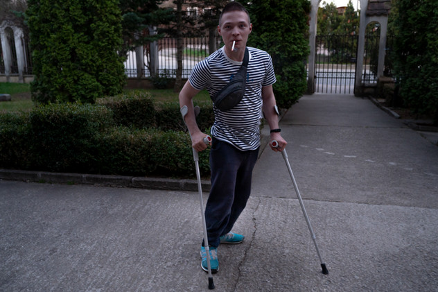 April 2022 | Iasi, Romania. Ihor G, 22 in the courtyard at Congregatia Flicelor Stinten Maria a Divinae Providentia - Don Guanella, in Bucium. Ihor was born with cerebral spastic infantile paralysis and lower spastic diplegia. He managed to take part of the evacuation from Mykolayiv thanks to a mayor's instagram post.