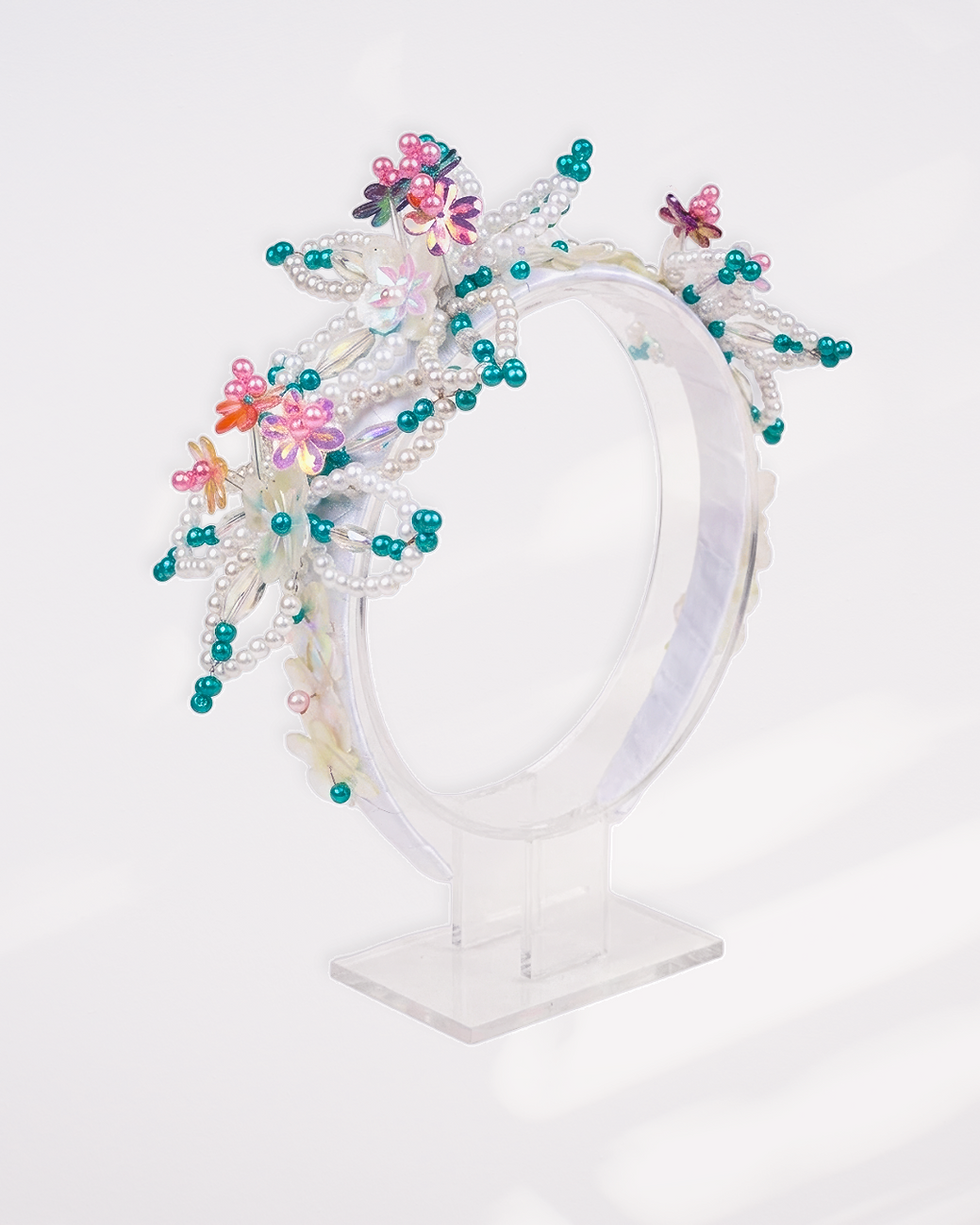 Tembleques personalizados en cintillo con cuentas blancas y flores.