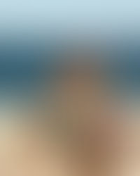 A atriz Camila Pitanga banhada pela luz do sol, posando majestosamente na icônica varanda de balaustrada branca do Copacabana Palace, com a areia da praia e o oceano azul desfocados ao fundo. Ela veste uma criação de alta-costura vanguardista e escultural, com um corset estruturado e inteiramente bordado com milhares de pedrarias, lantejoulas e cristais multicoloridos. A imagem ilustra o contraste entre o isolamento exclusivo e a blindagem do Copacabana Palace no Carnaval e a imensidão da praia.