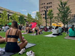 People in workout gear sitting on a green lawn in front of the Mall of America.